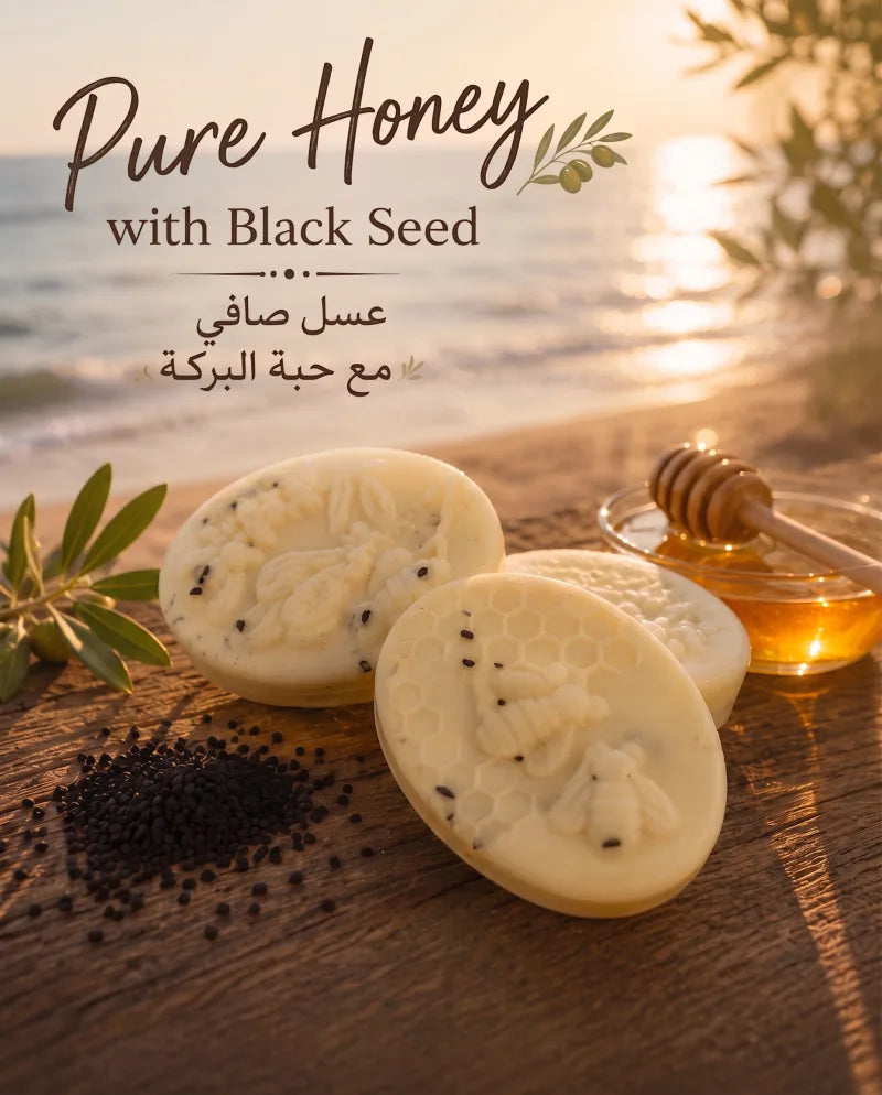 Honey and black seed soap ovals beside a honey dipper
